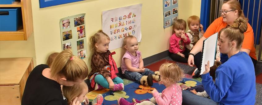 A student shows an image to a group of children in the classroom.