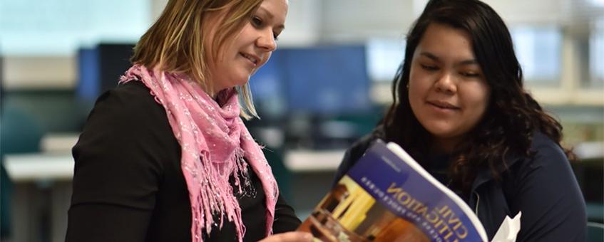 Two students in a Paralegal class looking at a Civil Litigation textbook.