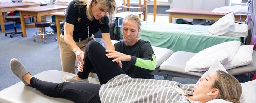 A Physical Therapist Assistant instructor working with two of her students.